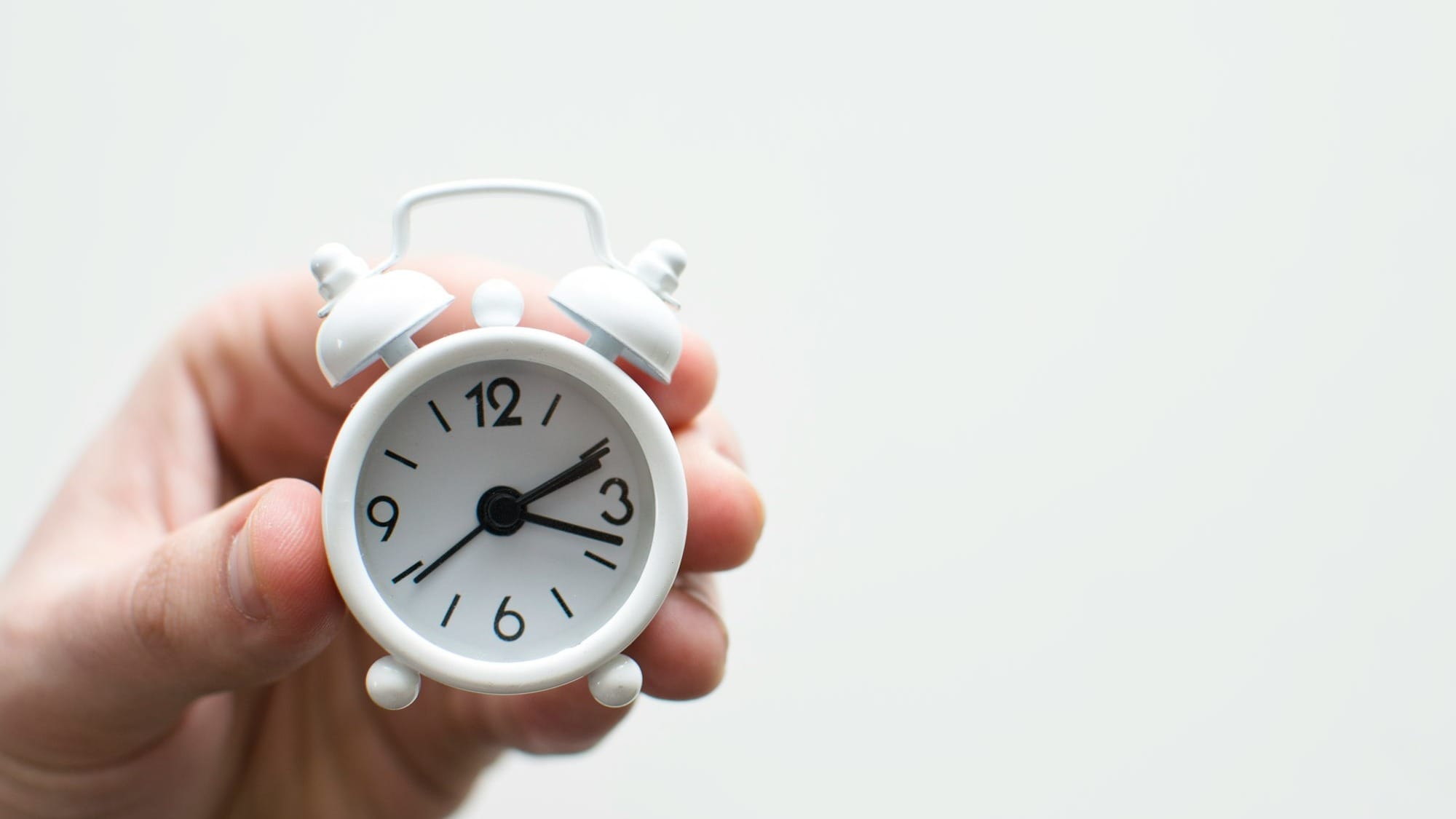person holding white mini bell alarmclock
